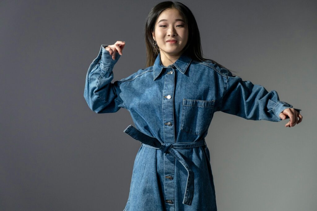 A fashionable woman poses confidently in a denim dress, showcasing modern style.
