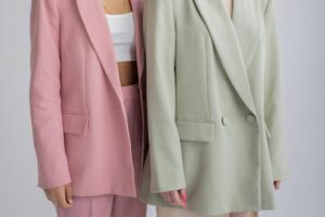 trendy clothes in 2026 Crop unrecognizable female models wearing oversize stylish outfits standing close against gray background in studio