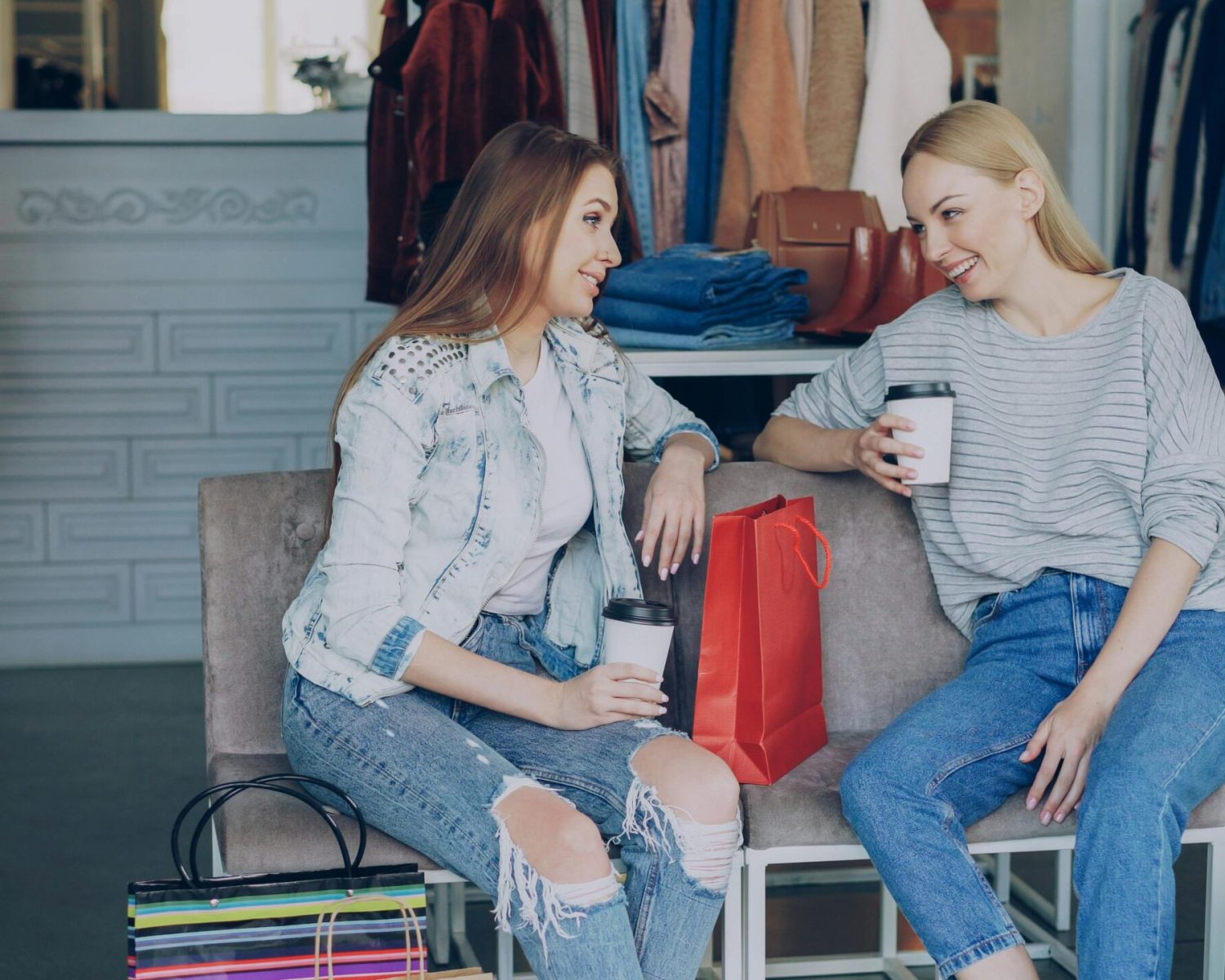 Two women share a coffee break while shopping in a boutique.